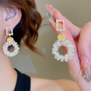 Detail of s925 gold earrings with pearl and crystal beads worn on ear for elegant style