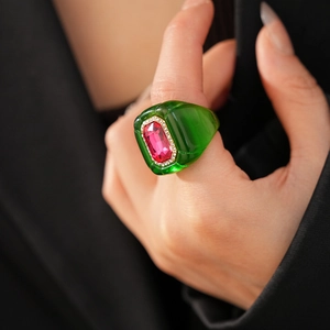 Détail macro d'une bague hexagonale en résine verte avec pierre rouge et cristaux