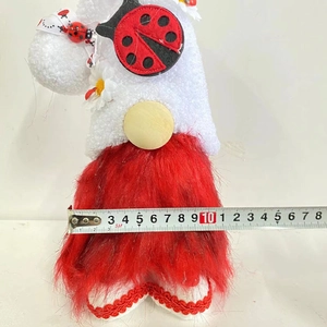 Red ladybug gnome plush toy with daisy decor shown with a ruler for size measurement