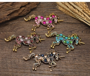 Detail of four retro alloy unicorn brooches with colorful rhinestones on a wooden surface