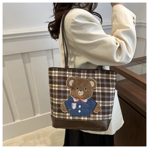 Detail of plaid tote bag featuring teddy bear embroidery and brown leather straps
