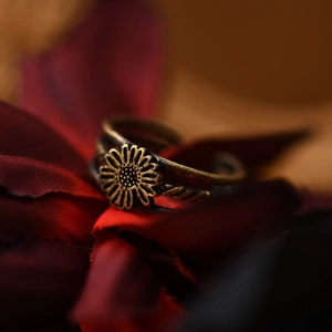 Vintage bronze sunflower open ring with antique finish on deep red velvet petals background
