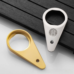 Close-up of gold and silver drop-shaped metal bottle openers with traditional engraving