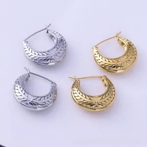 Detail of gold and silver textured hoop earrings with leaf pattern on purple background