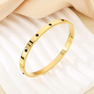 Detailed view of golden stainless steel bangle with black dotted inlay and LOU engraving