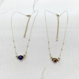 Detail of gold chain necklaces with tiger eye and lapis lazuli stone bead pendants