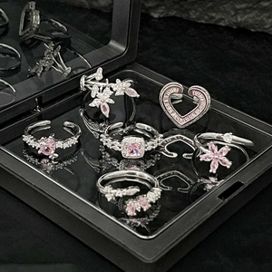 Detail of silver rings with pink heart and flower crystals in a black display box