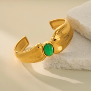 Detail of 18k gold plated open bangle featuring a centered oval green gemstone