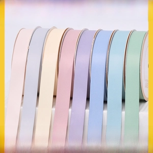 Detailed close-up of colorful satin ribbon rolls in Morandi pastel shades for gift wrapping