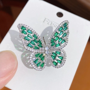 Macro shot of silver butterfly ring with emerald green stones and white crystal accents