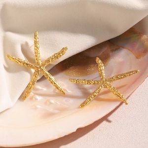Dettaglio degli orecchini a stella marina placcati oro 18K su conchiglie e tessuto