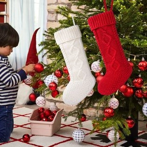 Close-up of knit Christmas stocking ornaments in red and beige under a tree
