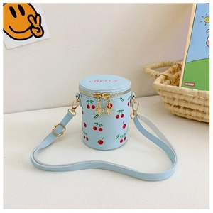 Close-up of light blue cherry print cylinder bag with gold zippers and adjustable strap