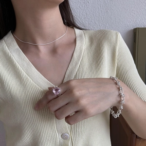 Detail of pink heart-shaped gemstone ring and silver jewelry worn by model
