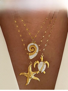 Detail of layered gold necklaces with starfish, sea turtle, and seashell pendants