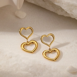 Detail of 18K gold plated double heart earrings on elegant light rock and sand background