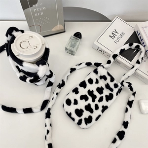 Detailed plush cow print water bottle holder and matching mini phone bag on desk