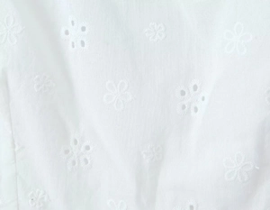 Détail de la broderie anglaise florale blanche sur le tissu d'un top d'été court