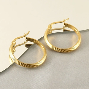 Detail of 18k gold plated hoop earrings with diagonal texture and snap closure