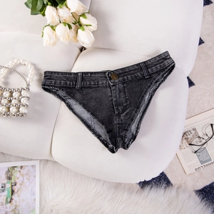Dettaglio degli shorts in denim grigio scuro elasticizzato con frange su divano in pelle