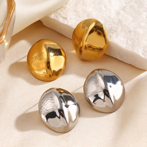 Polished gold and silver geometric oval stud earrings on beige silk and stone