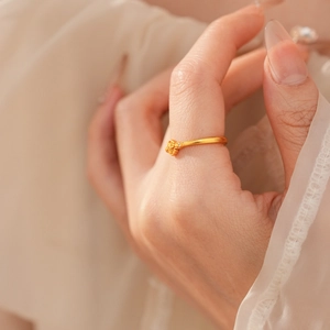 Dettaglio dell'anello vintage dorato con croce floreale sulla mano della modella