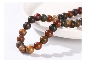 Macro detail of natural multi-color stone beads on a white ceramic tray with polished finish