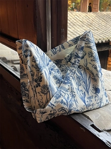 Detail of Toile de Jouy floral print on a large canvas tote bag against a wooden background