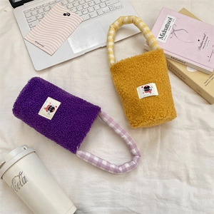 Detalle de bolsas de felpa moradas y amarillas con asas de cuadros y parches de dibujos