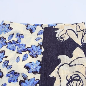 Détail de l'imprimé floral bleu sur la jupe midi en satin crème et sa texture plissée
