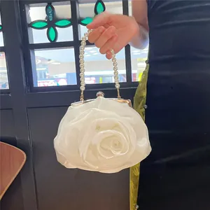 Macro detail of the 3D satin rose petals and white pearl handle on this bridal clutch
