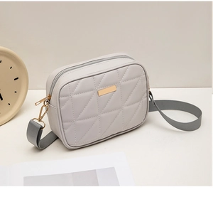 Detailed close-up of light grey quilted leather crossbody bag with dual zippers