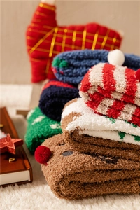 Close-up of fluffy Christmas coral fleece socks with elk decor in warm indoor setting