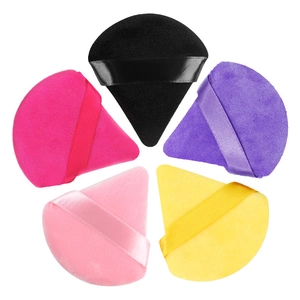 Detailed view of five colorful velvet triangular makeup puffs with satin ribbon handles