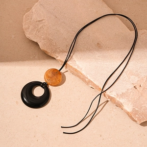 Detail of amber marble resin pendant and black ring on textured rock display
