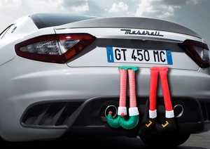 Whimsical plush Santa elf legs hanging from a car trunk for festive holiday decoration