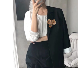 Detail of elephant brooch with brown gems pinned on black blazer for winter fashion