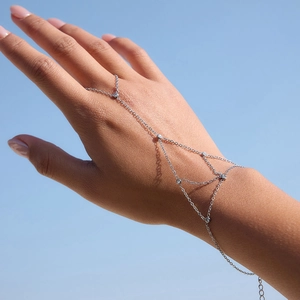 Elegant silver slave bracelet with sparkling zircons worn against a clear blue sky background