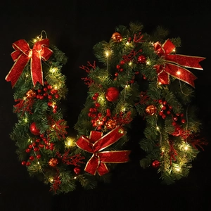 Lush green Christmas garland with red bows, berries, ornaments and warm white LED lights