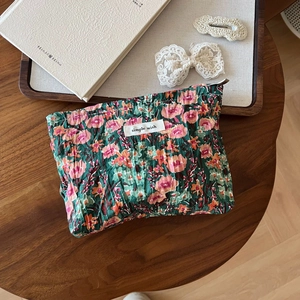 Detail of green floral pouch with pleated texture and simple wish label on wood