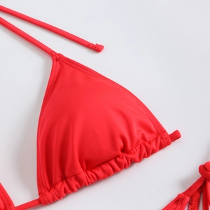 Close-up of red ribbed bikini top showing halter neck ties and pleated cup details