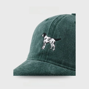 Close-up of dog embroidery on washed dark green cotton baseball cap fabric texture