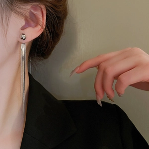 Close-up of elegant long silver tassel earrings worn by model showing metallic texture
