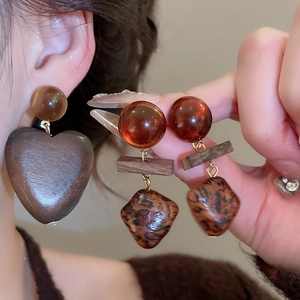 Gros plan sur des boucles d'oreilles cœur en bois rétro et des clous en résine léopard