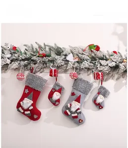 Detailed view of red and grey knitted Christmas stockings with 3D gnomes on pine branches