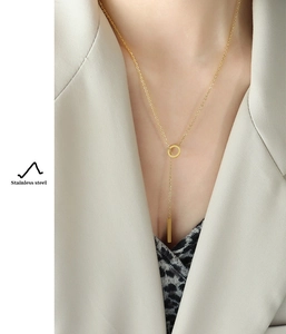 Detail view of gold Y-shaped stainless steel necklace with fringe tassel on a model