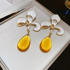 Detail of floral enamel earrings with white petals and amber resin water drop charms