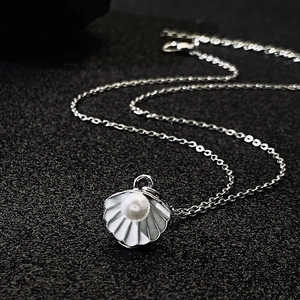 Detailed close-up of a silver shell necklace with an elegant white pearl inlay
