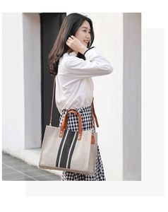 Detail of canvas tote bag with brown leather handles and vertical stripes for women