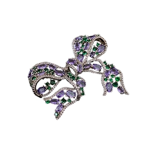 Elegant bow-shaped brooch with purple and green crystals and silver-tone metal